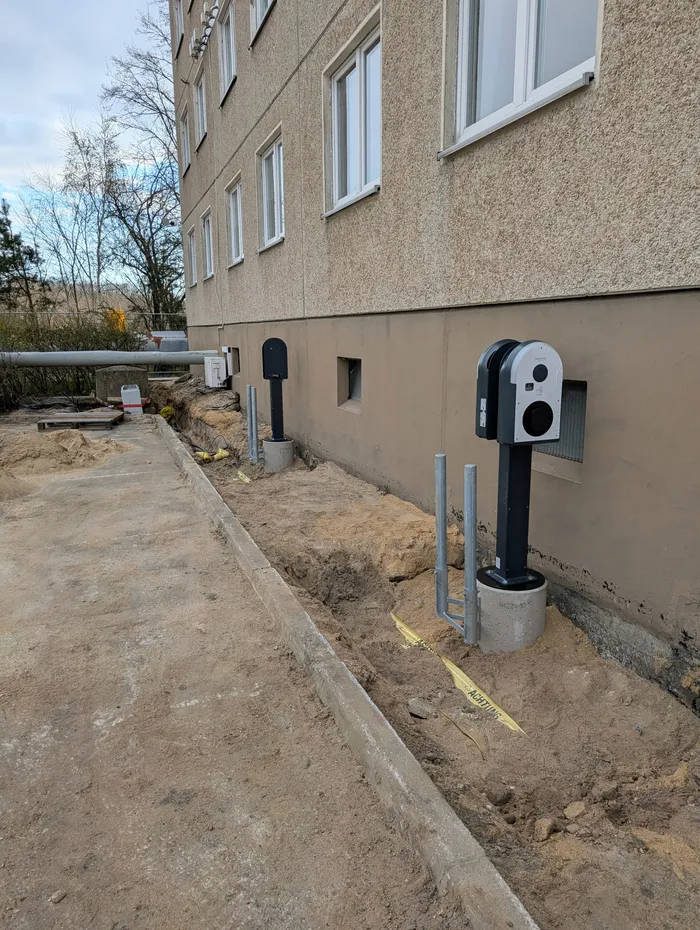 Montage einer Wallbox auf Betonfundament während der Bauphase, daneben die offene Kabeltrasse